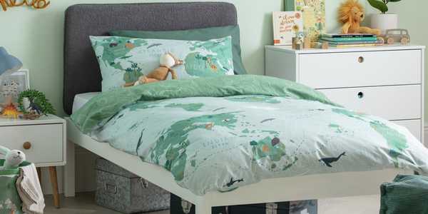 A kid's room with a grey and white bed frame with green coloured world-map print bedding.